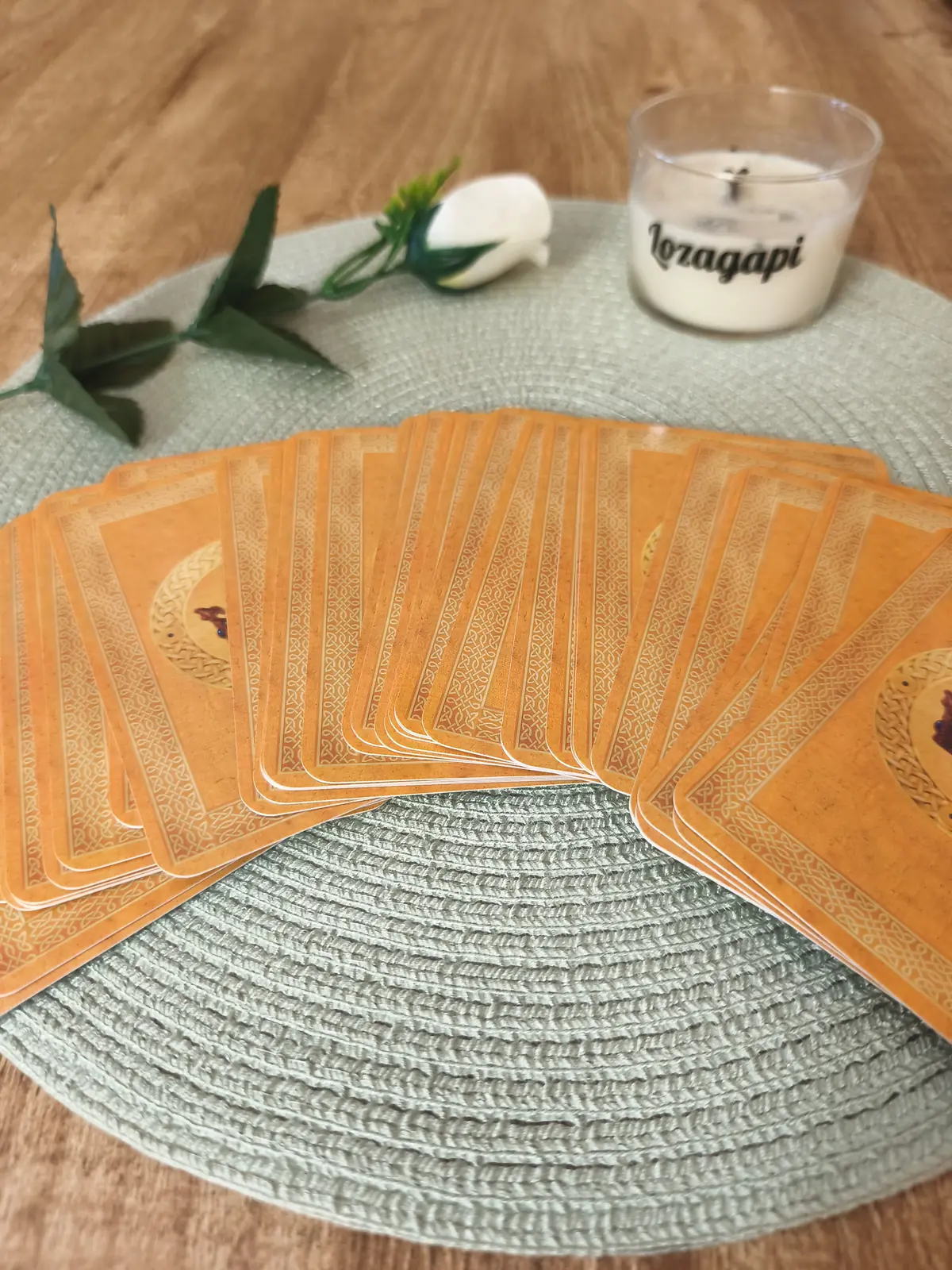 Cartas del Oráculo de Diosas extendidas en abanico sobre un mantel verde, con una vela de Lozagapi y una rosa blanca